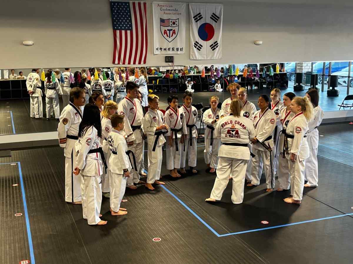 children and teens taekwondo students listening to instructions