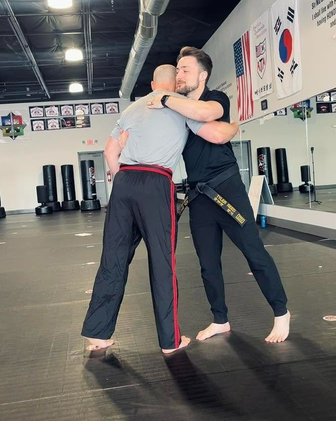 Two adult martial artists practicing a close-range grappling technique during class, demonstrating practical skills from an adult martial arts training guide.