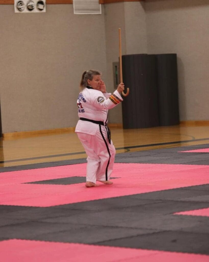 Adult martial artist demonstrating a traditional weapon form during competition, practicing coordination with an adult martial arts training guide.