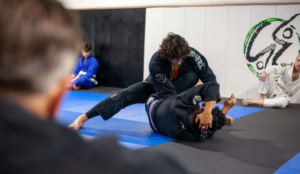 Two martial artists practicing ground grappling during beginner martial arts training