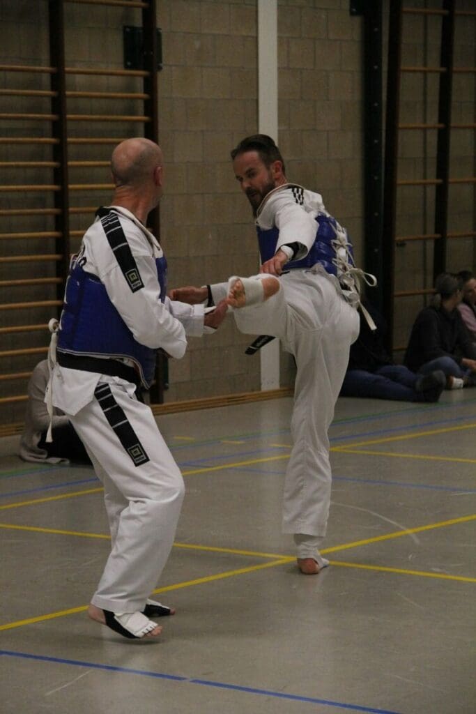 Two martial artists practicing a controlled kick during beginner martial arts training
